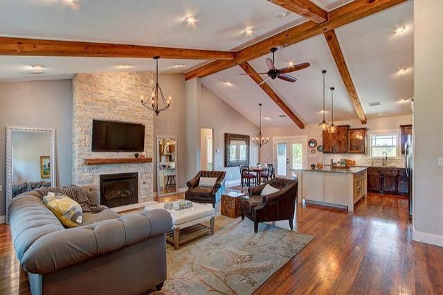 A full shot of a living room with a fireplace, sofa, wooden musk floor, carpet, and a tall ceiling.